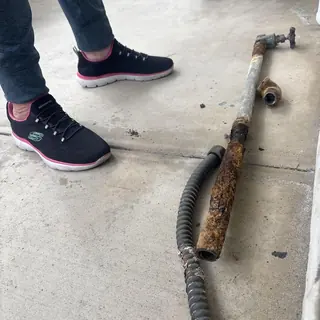 Rusty water main pipe and valve removed on concrete floor